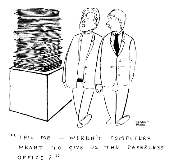 Two businessmen passing huge pile of paper on desk. One says: 'Tell 
me - weren't computers supposed to give us the paperless office?'
